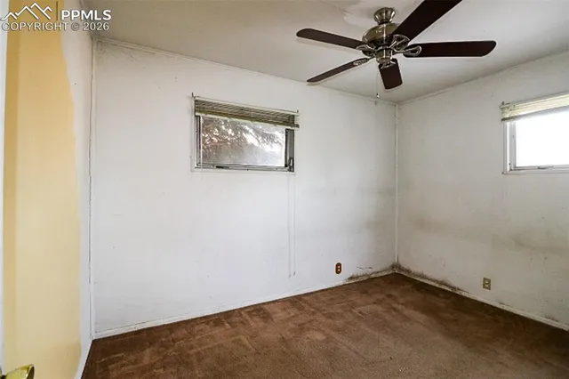 an empty room with a fan & a window