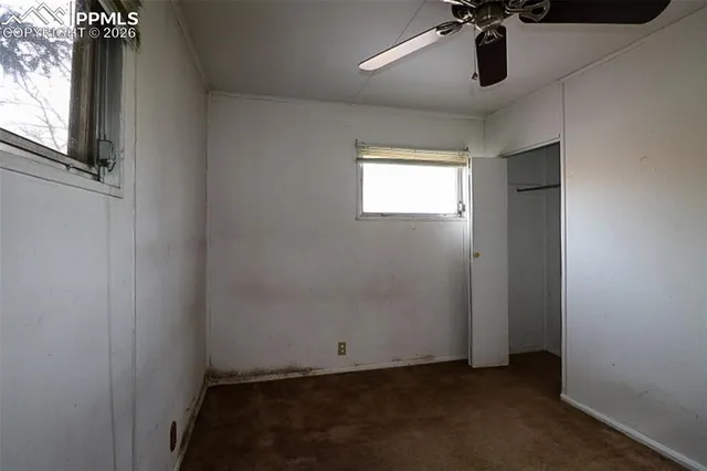 an empty room with a ceiling fan and window