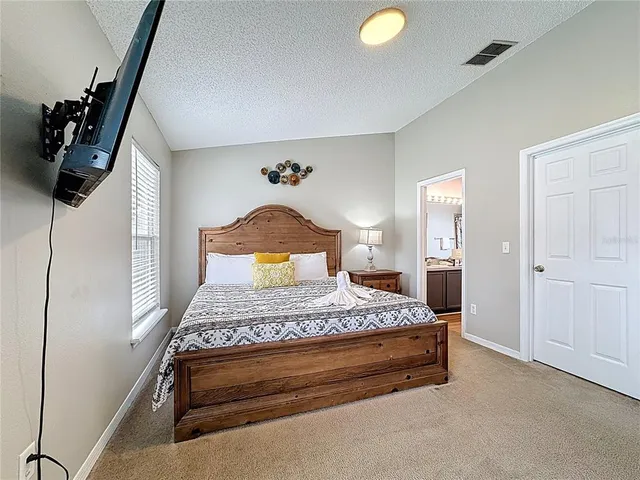 a bedroom with a bed and a flat tv screen on dresser