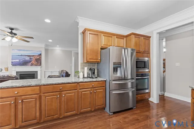 a kitchen with stainless steel appliances granite countertop a stove a sink dishwasher and microwave with wooden cabinets