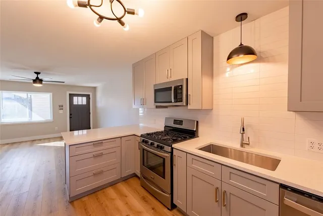 a kitchen with stainless steel appliances granite countertop a sink a stove and a wooden floors