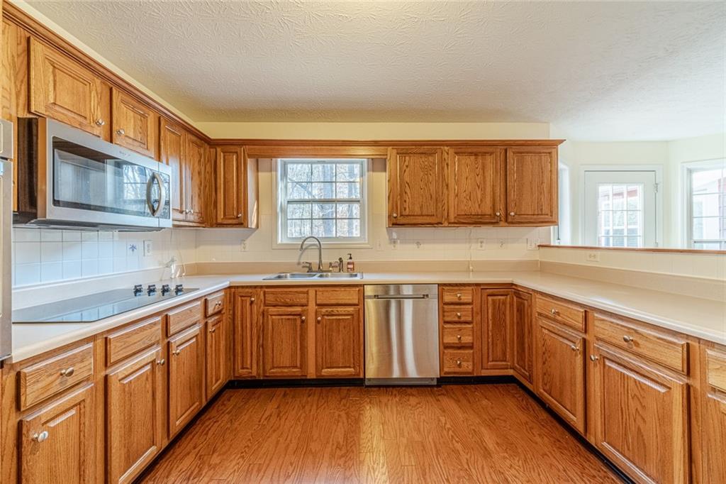 3240 Stewart Lake Road Monroe, GA 30655 - Photo 16 of 68 a kitchen with stainless steel appliances granite countertop wooden cabinets a sink and dishwasher a stove with wooden floors