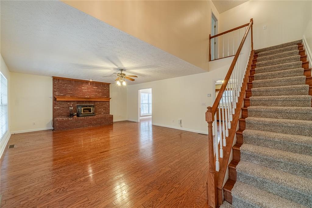 3240 Stewart Lake Road Monroe, GA 30655 - Photo 5 of 68 a view of a livingroom with wooden floor staircase and a ceiling fan