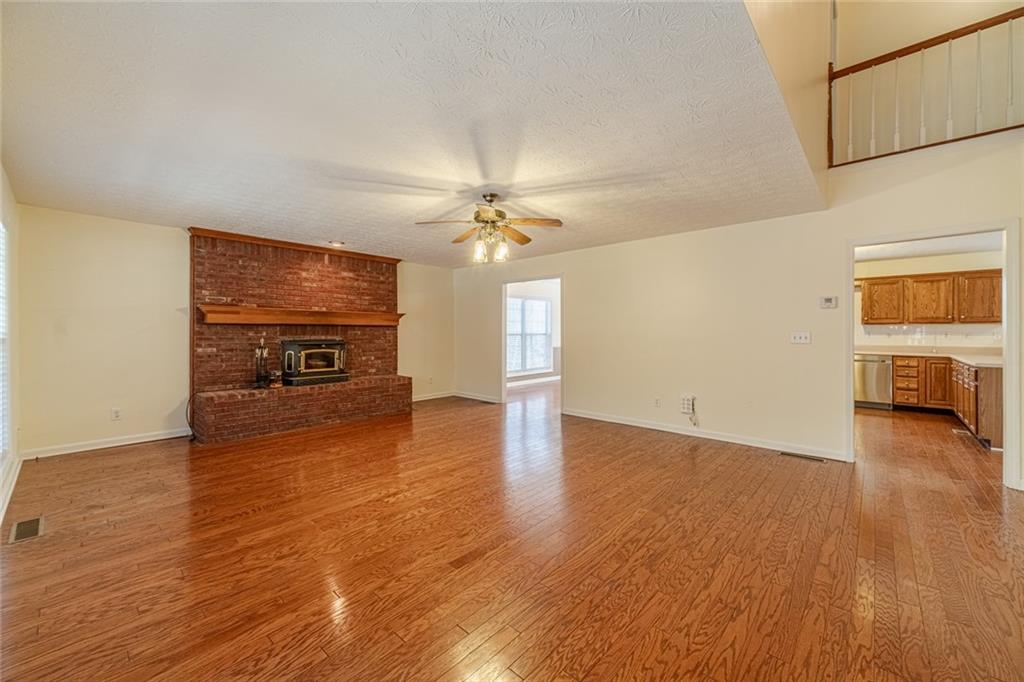 3240 Stewart Lake Road Monroe, GA 30655 - Photo 6 of 68 a view of empty room with wooden floor and a fireplace