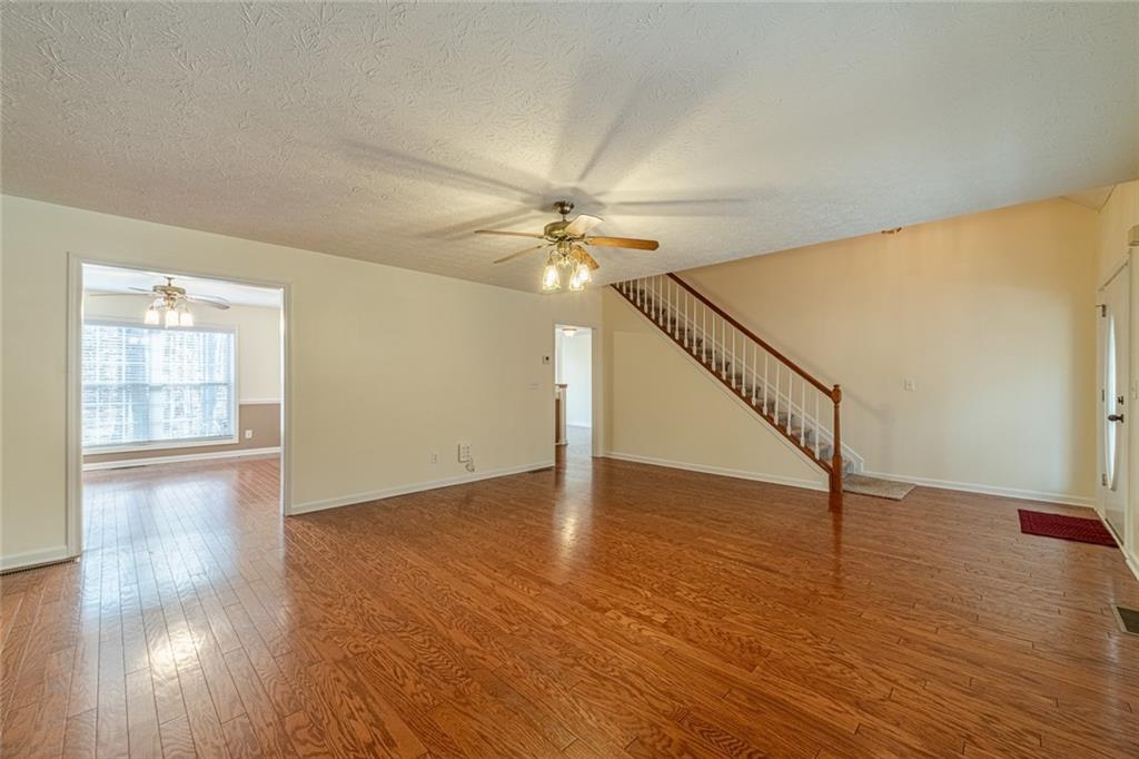 3240 Stewart Lake Road Monroe, GA 30655 - Photo 7 of 68 a view of an empty room with wooden floor and a ceiling fan