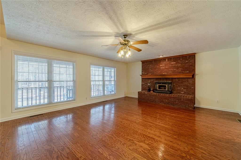 3240 Stewart Lake Road Monroe, GA 30655 - Photo 9 of 68 an empty room with windows a fireplace and wooden floor