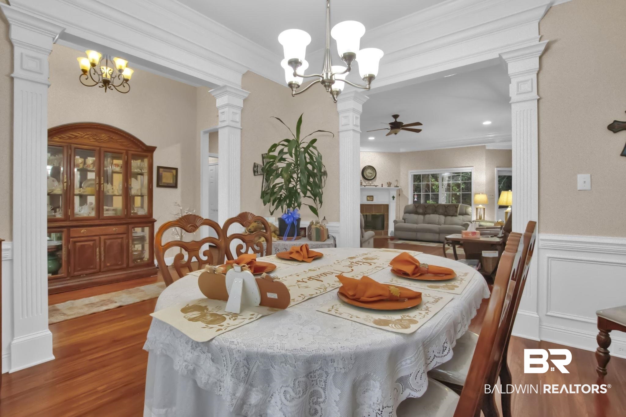 1 Bens Bluff Daphne, AL 36527 - Photo 15 of 56 Dining area with a tiled fireplace, crown molding, ceiling fan with notable chandelier, ornate columns, and dark hardwood / wood-style floors
