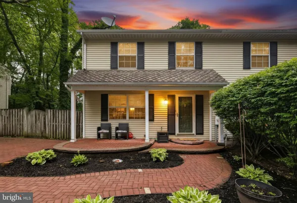 a view of a brick house with a small yard plants and large tree
