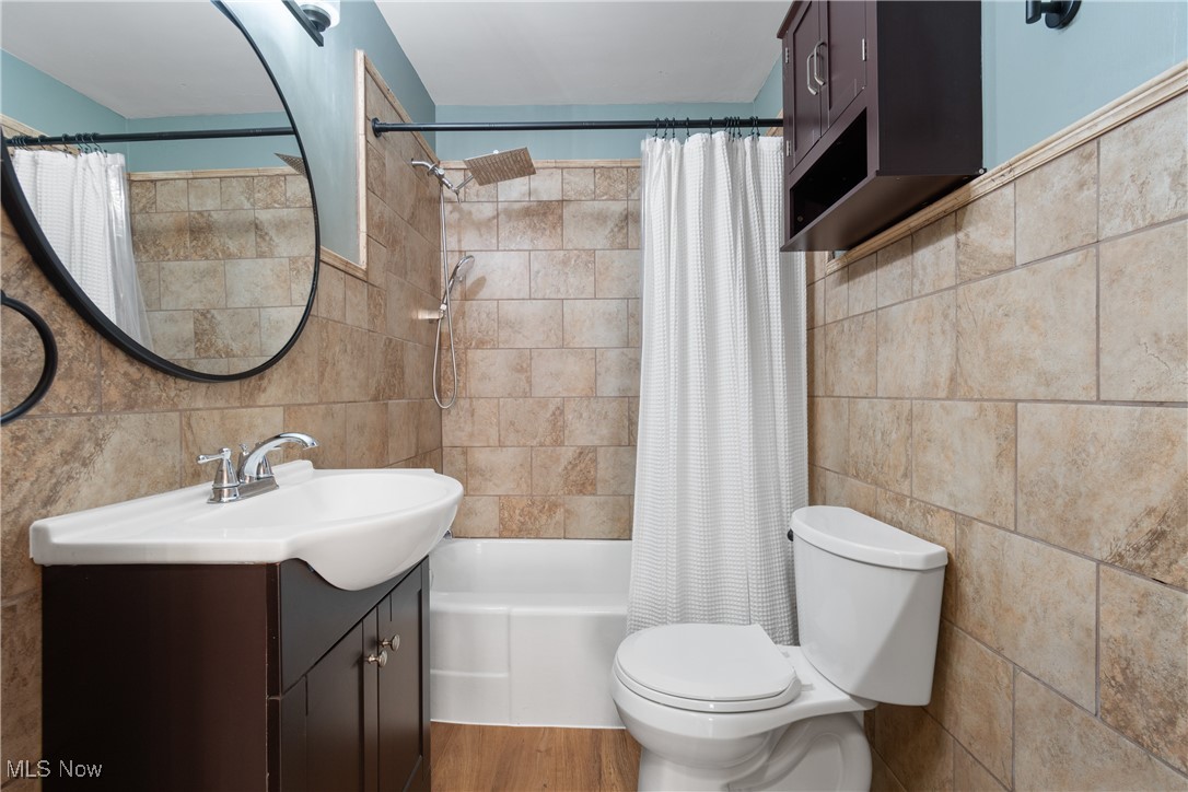 56321-56323 Riley Road Bridgeport, OH 43912 - Photo 13 of 40 Full bathroom featuring toilet, shower / bathtub combination with curtain, tile walls, vanity, and decorative backsplash