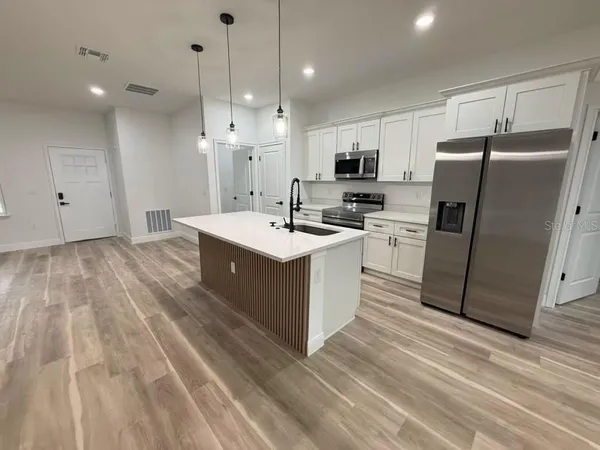 a large kitchen with stainless steel appliances granite countertop a sink and a refrigerator