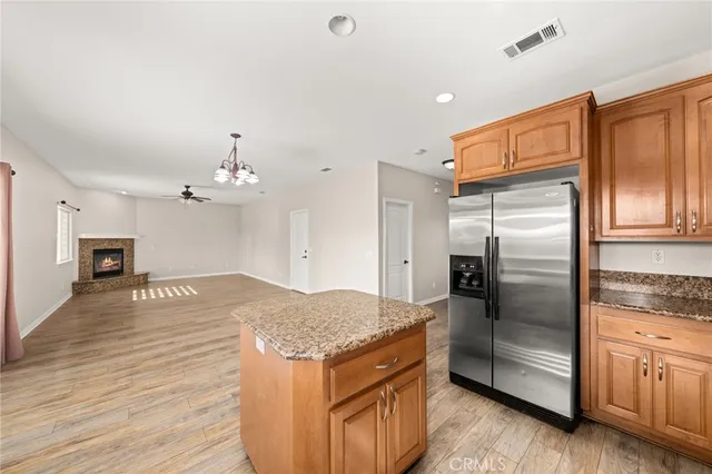 a kitchen with stainless steel appliances granite countertop a refrigerator a stove and a sink with wooden floor
