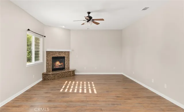 a view of an empty room with wooden floor a fireplace and a window