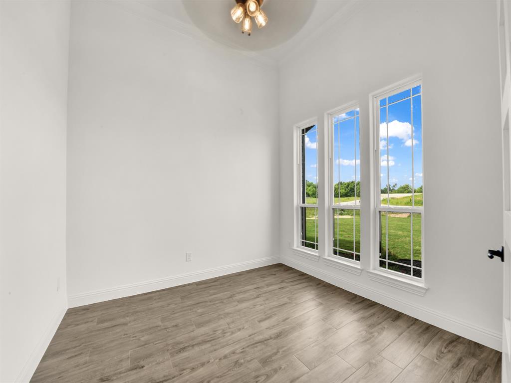 143 Desperado Way Weatherford, TX 76088 - Photo 34 of 36 Empty room featuring ceiling fan, wood finished floors, baseboards, and crown molding