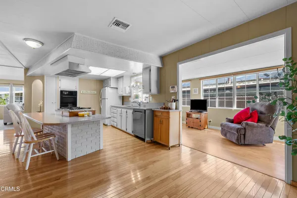 a living room with stainless steel appliances kitchen island granite countertop a stove and a large window