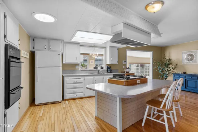 a kitchen with stainless steel appliances granite countertop a refrigerator a stove a sink dishwasher and white countertops with wooden floor