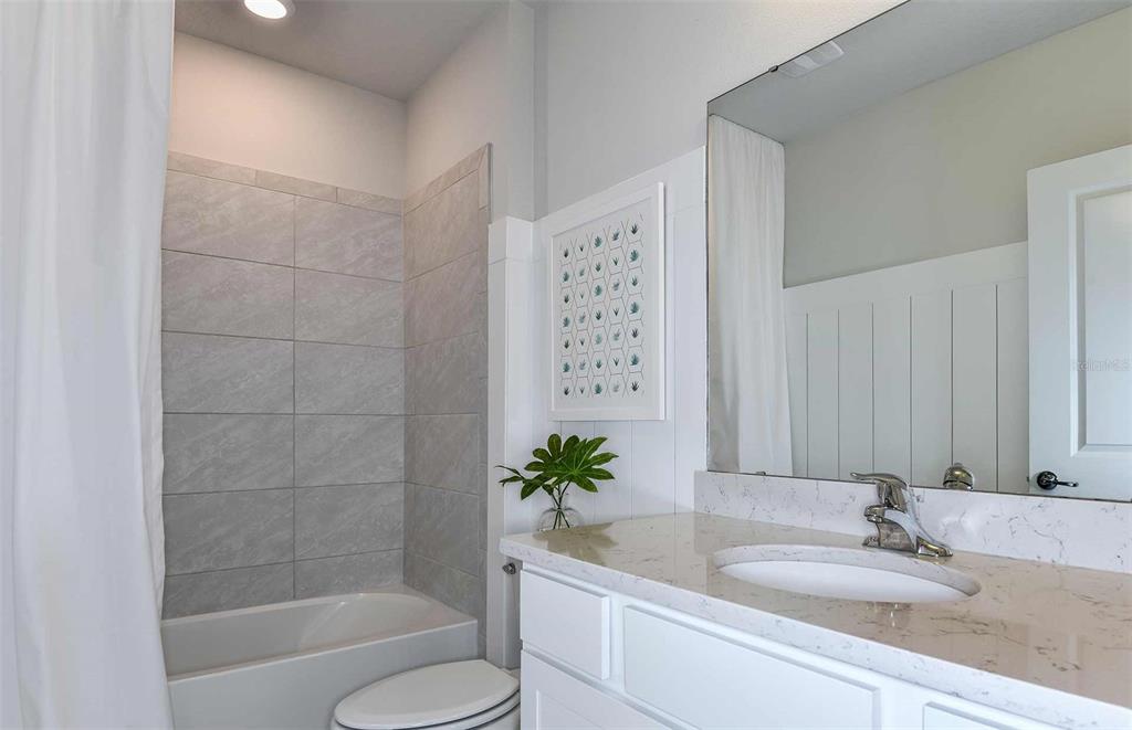 12816 Blue Reflection Avenue Parrish, FL 34219 - Photo 10 of 12 a bathroom with a granite countertop sink a toilet and shower