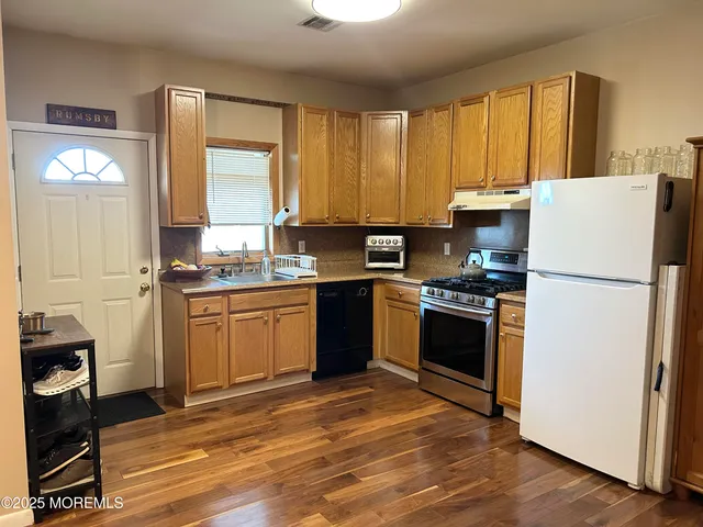 a kitchen with granite countertop a refrigerator stove top oven and sink
