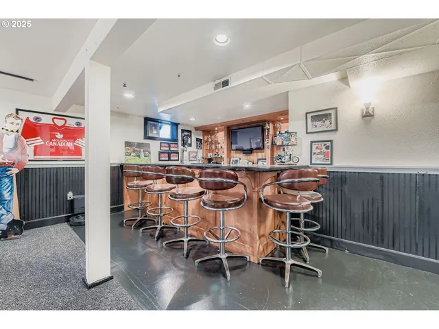 a kitchen with stainless steel appliances kitchen island granite countertop a dining table chairs and a refrigerator