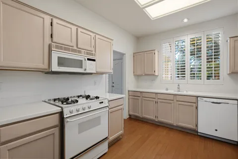 a kitchen with stainless steel appliances granite countertop white cabinets and window