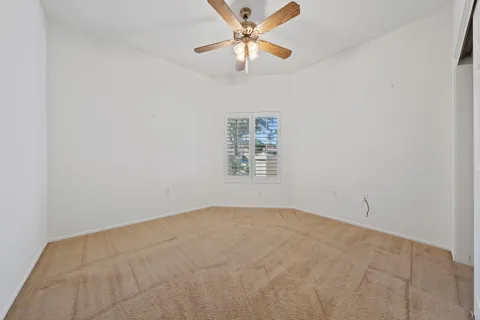 an empty room with a window and a ceiling fan
