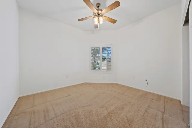an empty room with a window and a ceiling fan