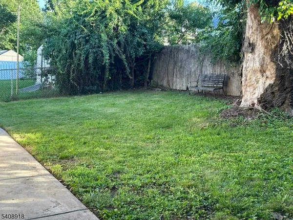 a view of a backyard with large trees and wooden fence