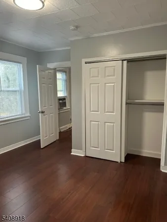 an empty room with wooden floor closet and windows