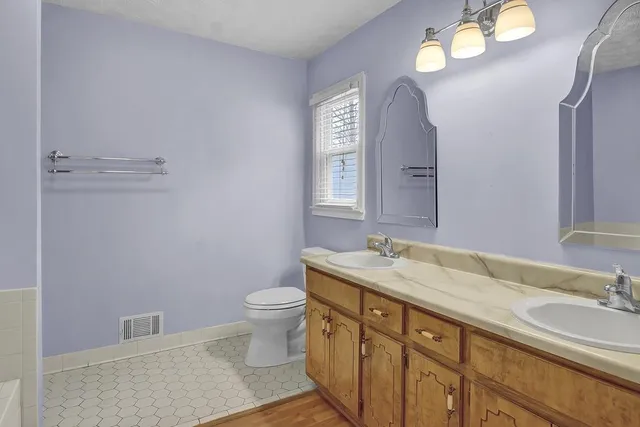 a bathroom with a granite countertop sink a toilet and a mirror