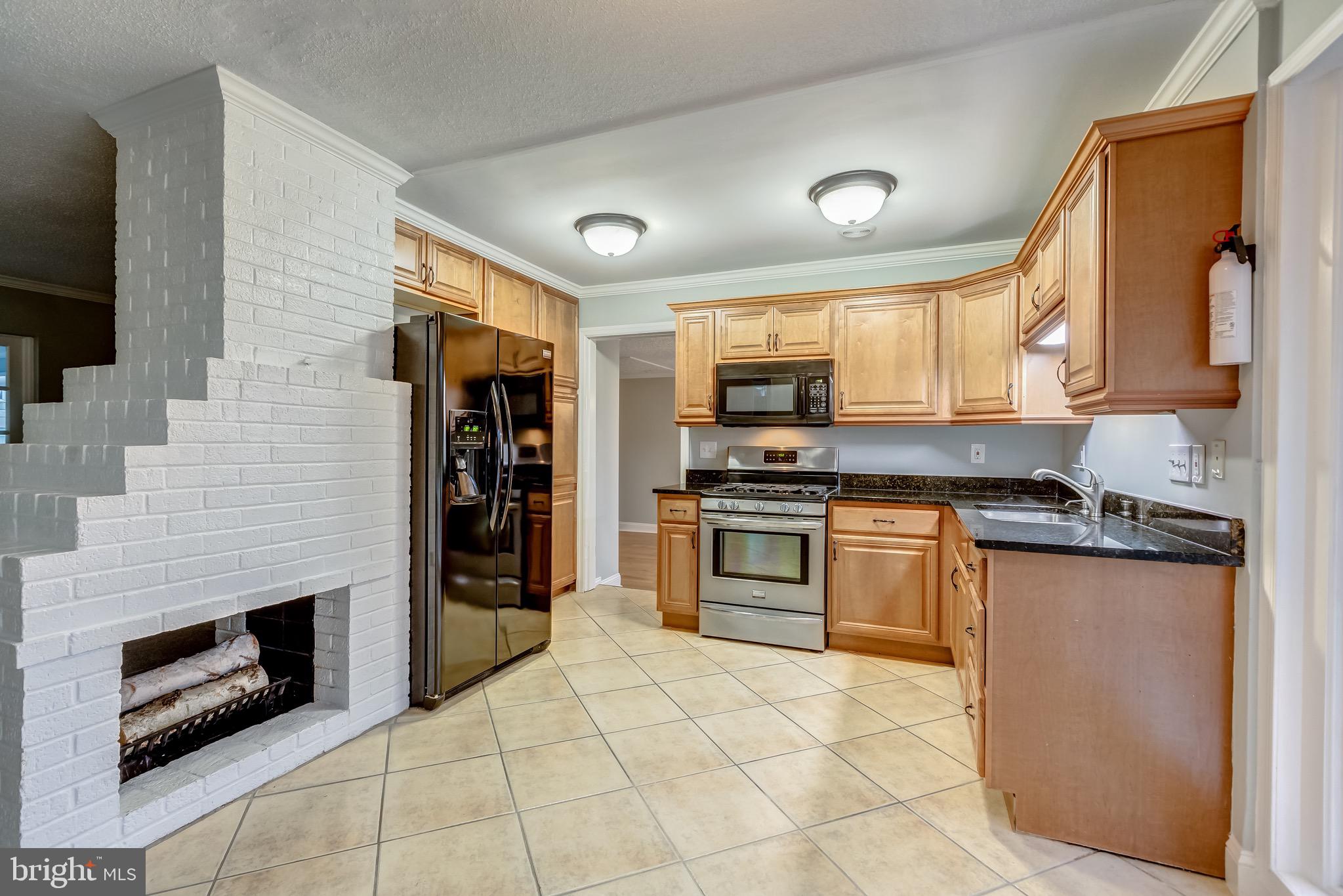 7303 Dickenson Street Springfield, VA 22150 - Photo 11 of 41 Wood burning fireplace dividing kitchen/lvg rm