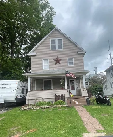 a front view of a house with a garden and trees