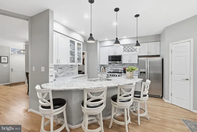 a kitchen with stainless steel appliances kitchen island granite countertop a dining table chairs and white cabinets