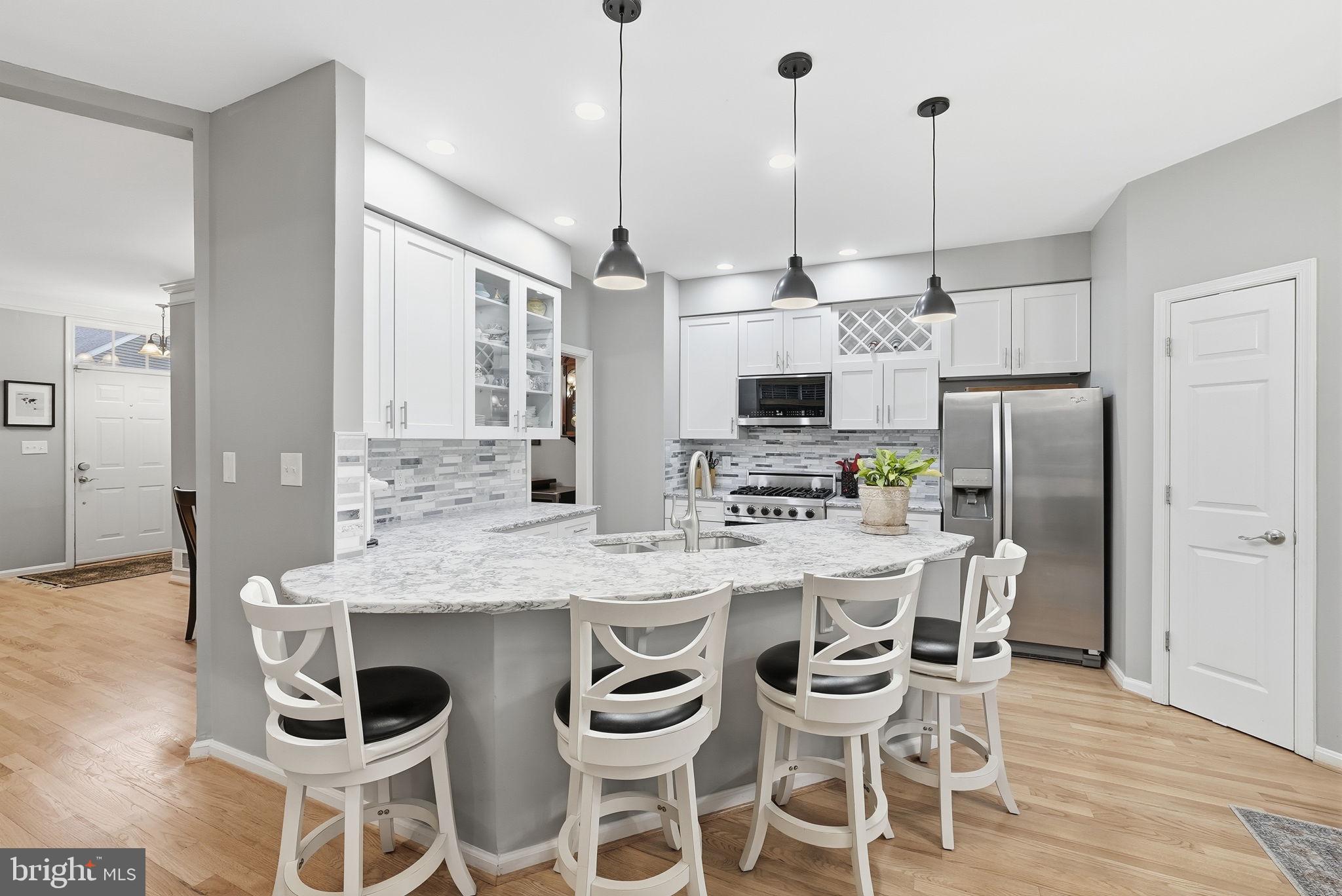 11411 Hollow Timber Court Reston, VA 20194 - Photo 15 of 46 a kitchen with stainless steel appliances kitchen island granite countertop a dining table chairs and white cabinets