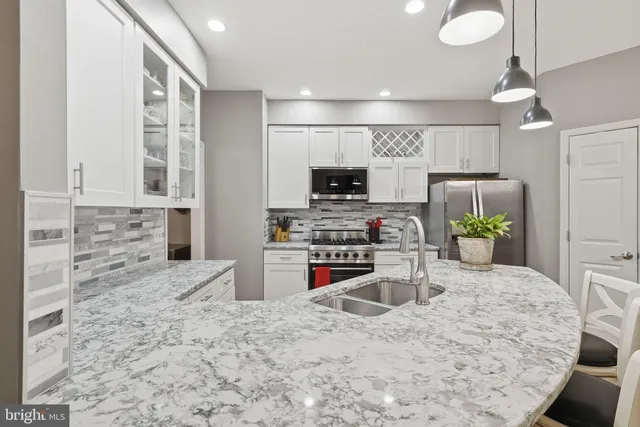 a kitchen with stainless steel appliances kitchen island granite countertop a stove sink and cabinets