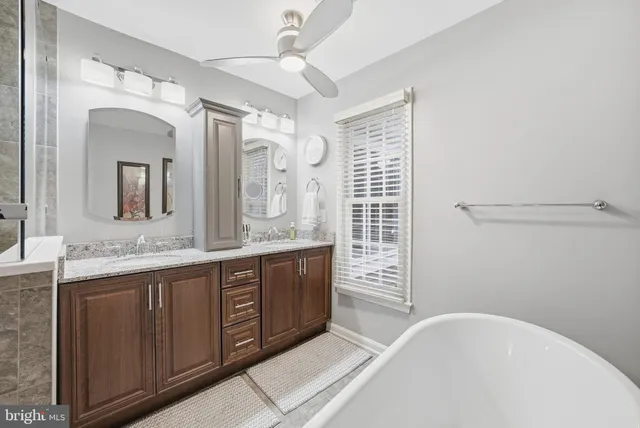 a spacious bathroom with a granite countertop sink mirror and bathtub