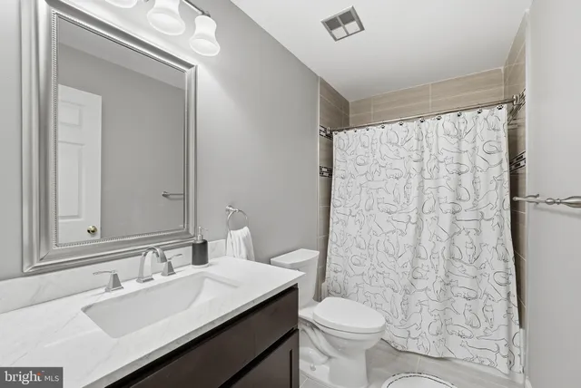 a bathroom with a sink a toilet a mirror and shower curtain