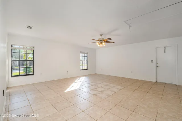 a view of an empty room with window and chandelier fan