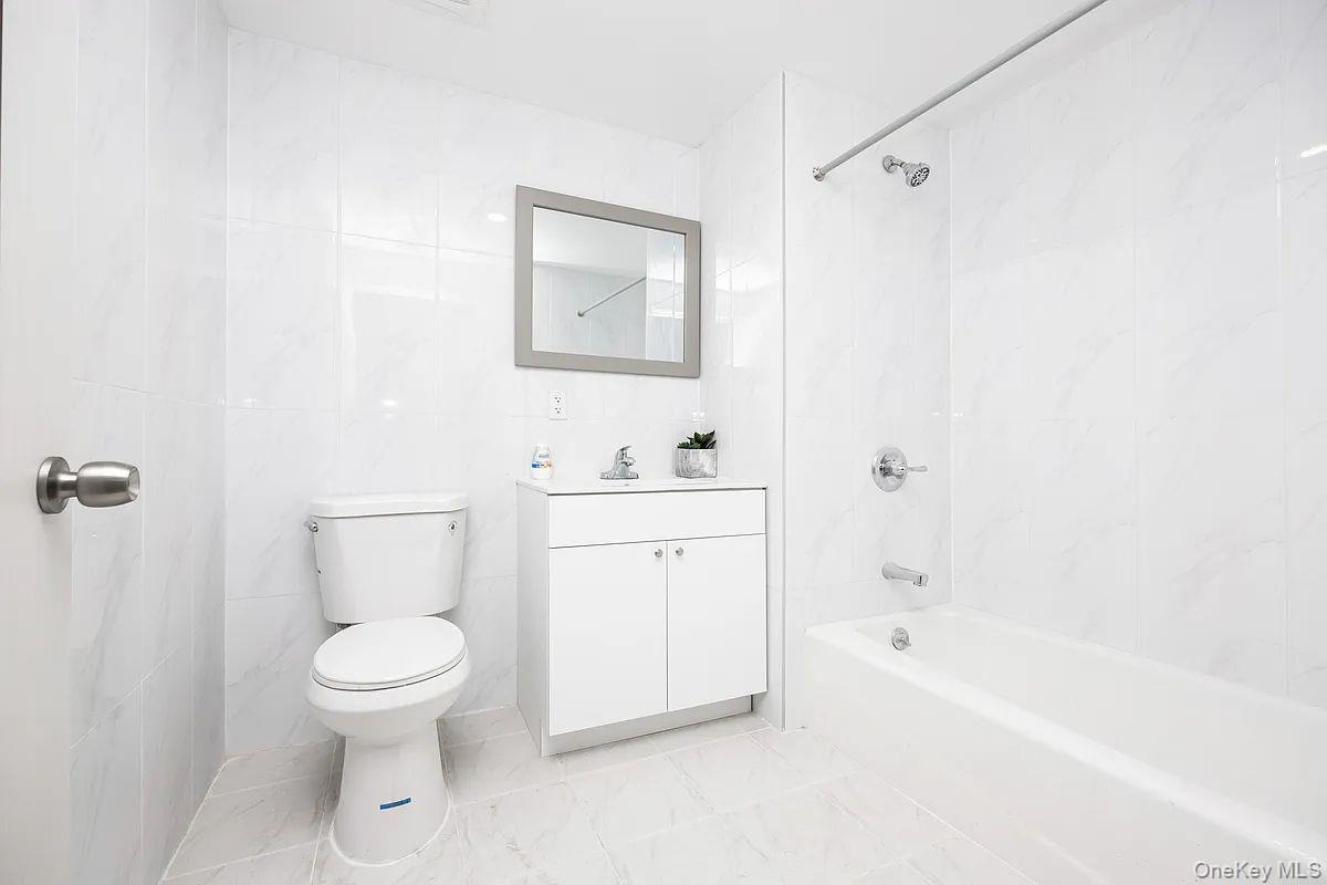 70-40 45th Avenue, Unit 7K Queens, NY 11377 - Photo 3 of 4 Full bathroom featuring shower / tub combination, vanity, and tile walls