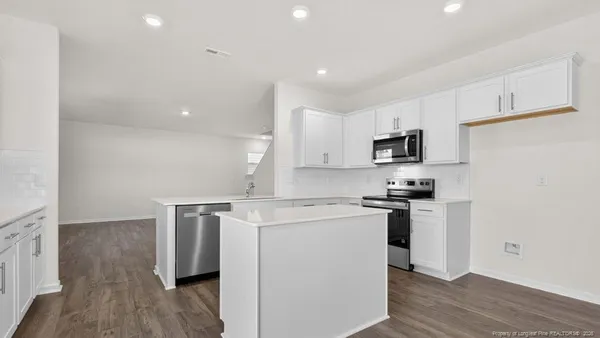 a kitchen with a sink a stove a refrigerator and white cabinets