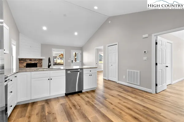 a kitchen with a sink cabinets stainless steel appliances and wooden floor