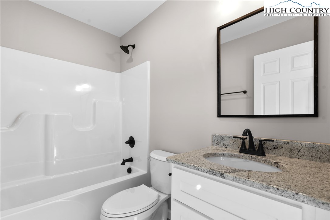 233 Ava Way, Unit 109 Boone, NC 28607 - Photo 17 of 26 a bathroom with a granite countertop sink a toilet a mirror and shower