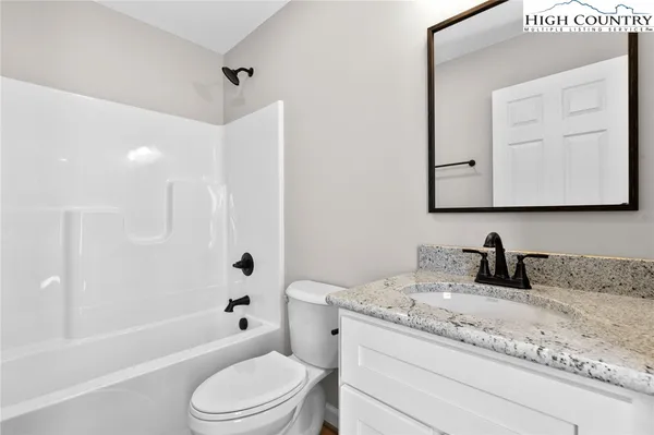 a bathroom with a granite countertop sink a toilet and a bathtub