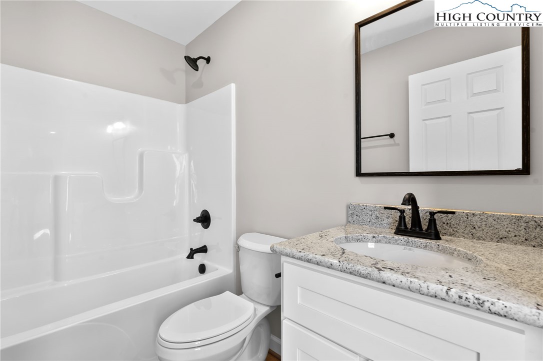 233 Ava Way, Unit 109 Boone, NC 28607 - Photo 20 of 26 a bathroom with a granite countertop sink a toilet and a bathtub