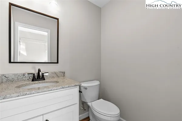 a bathroom with a toilet sink vanity and mirror