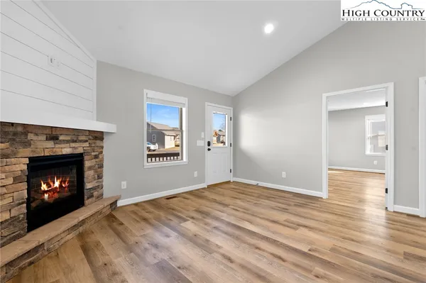 a view of an empty room with wooden floor fireplace and a window