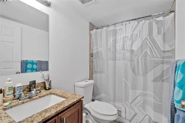 a bathroom with a granite countertop sink toilet and shower