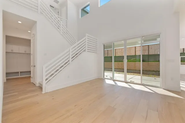 a view of an empty room with wooden floor and windows