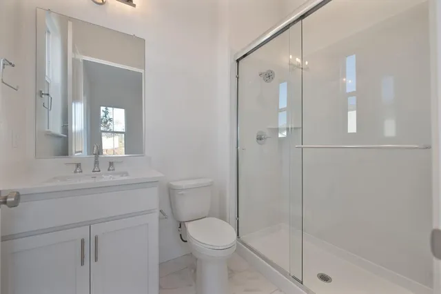 a bathroom with a toilet sink vanity granite and shower