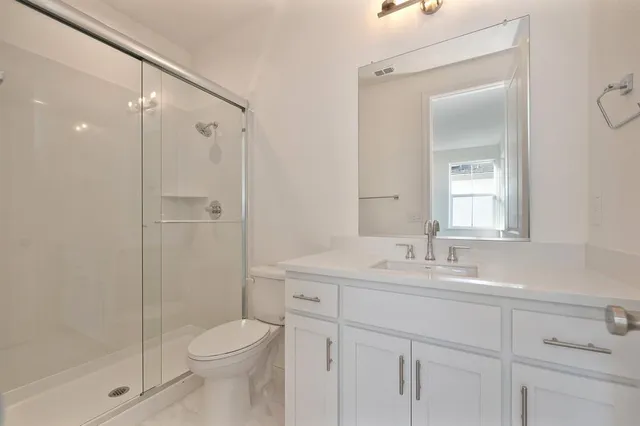 a bathroom with a sink toilet vanity and shower