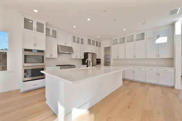 a large white kitchen with a stove top oven a sink and dishwasher with wooden floor