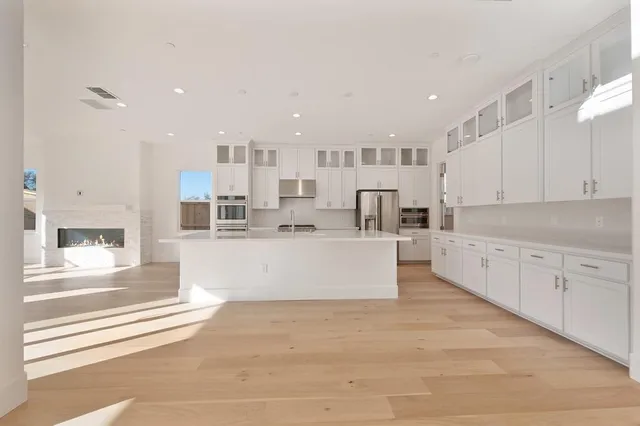 a large white kitchen with kitchen island a stove a sink a refrigerator and white cabinets